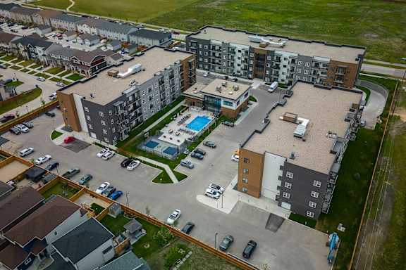 An aerial view of apartment buildings with a pool in the courtyard.