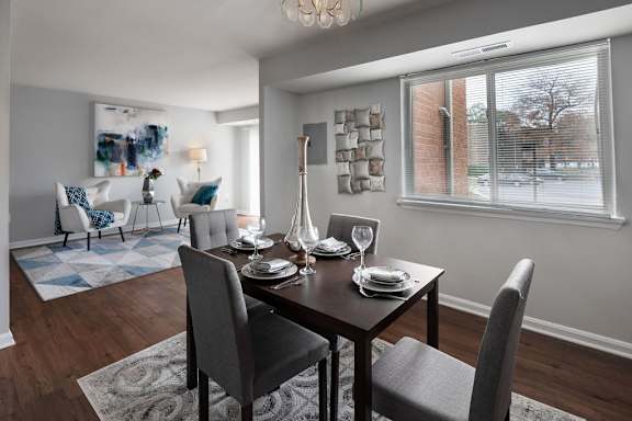 A dining room with a table set for two and a view of a street outside.