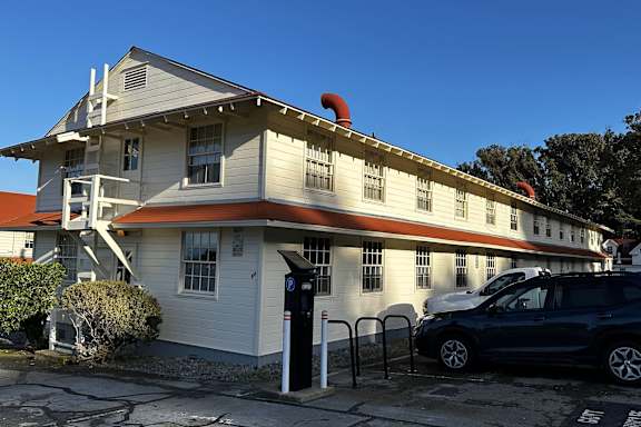 a white building with an orange and white roof and a car parked outside