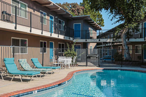 A pool is surrounded by chairs and tables in front of a building at Pennsylvania Place, California
