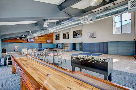 A long wooden table is in the middle of a room with a basketball hoop in the background.