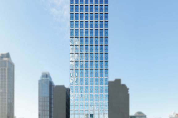 A tall building with blue glass windows stands in front of other buildings.