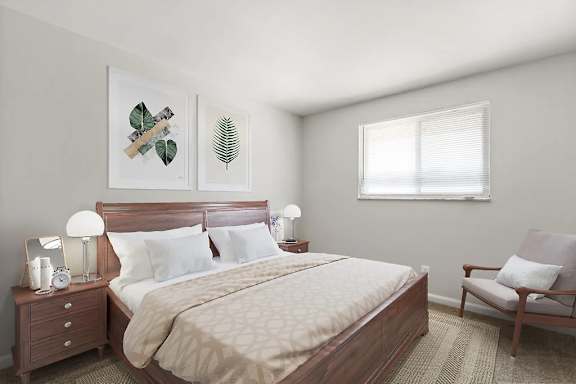 A bedroom with a bed, chair, and two framed leaves on the wall.