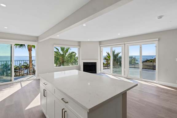 A modern kitchen with a large island and a view of the ocean.