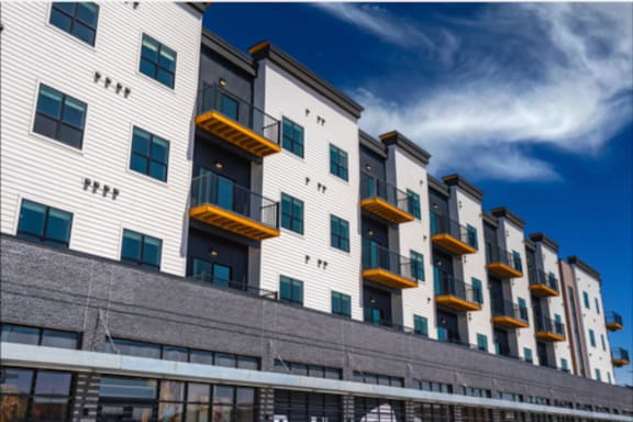 A modern building with balconies and a clear blue sky in the background.