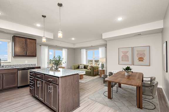 A modern kitchen with a wooden island and a dining table set up at Decatur Landing Apartment , Brooklyn Park, 55445
