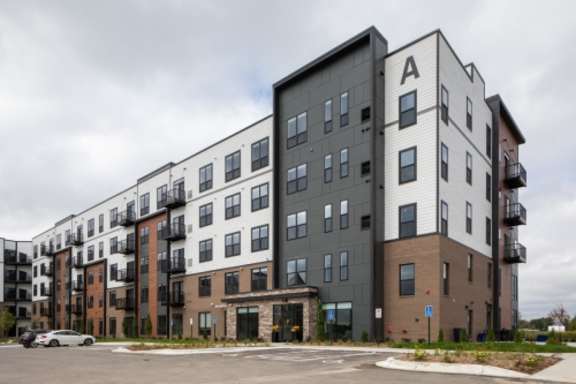 Apartment building with a car parked in front.at The Edison at Maple Grove, Maple Grove, MN