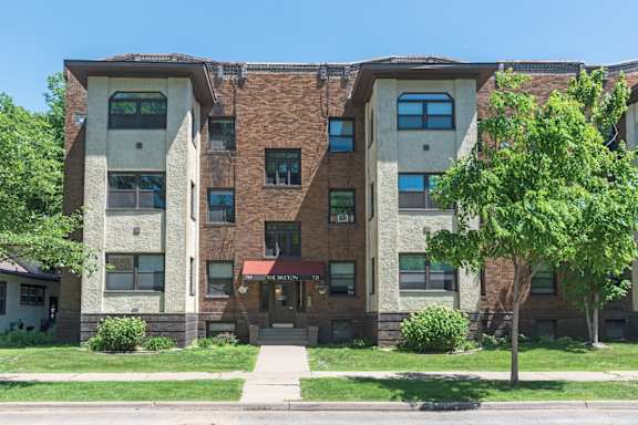 an apartment building with a tree in front of it