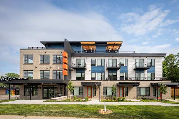 the front of a modern apartment building with balconies and a lawn
