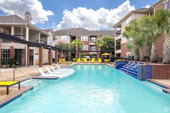 A swimming pool with yellow chairs and a blue fence.