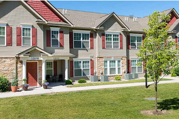 View of exterior of apartment building with private front entrances, landscaping, and sidewalks