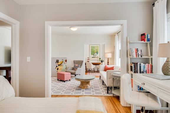 A living room with a white couch and a painting on the wall.