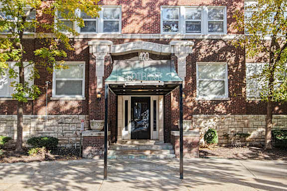 A red brick building with a green awning and a black door.