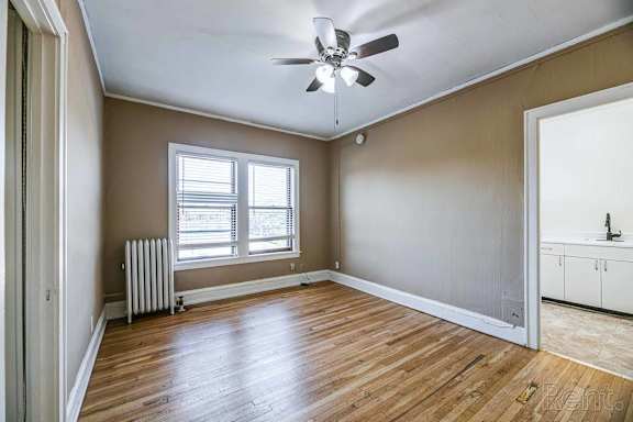 A room with a ceiling fan and wooden flooring.