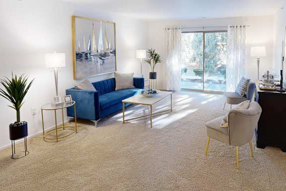 A living room with a blue sofa and a painting on the wall.