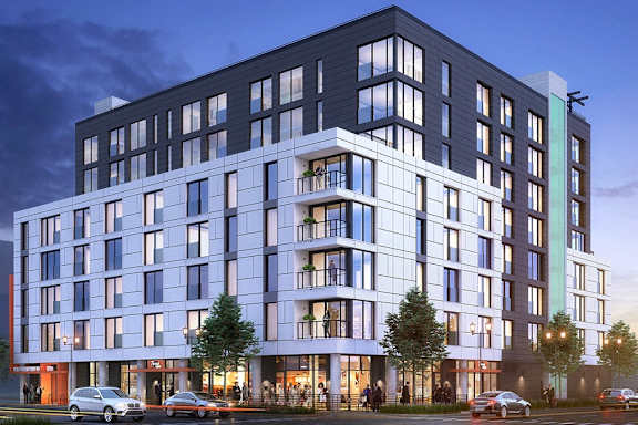 A modern multi-story building with a parking lot in front.