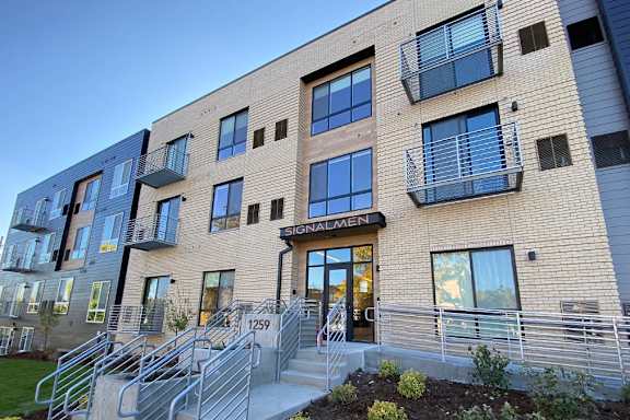 The image shows a modern building with a glass entrance and a sign that reads "Signalmen."