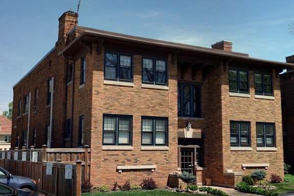 A red brick house with a car parked in front.