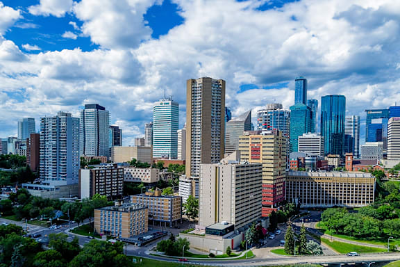 A cityscape with tall buildings and a cloudy sky.