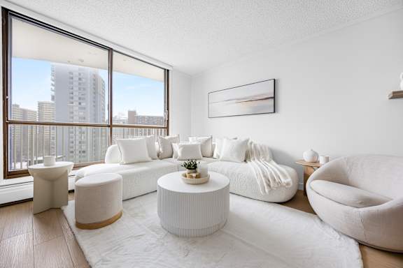 A modern living room with white furniture and a large window overlooking a cityscape.