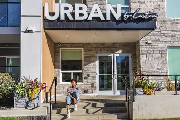 A person is sitting on the steps outside the URBAN building.