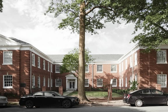A black car is parked in front of a red brick building.