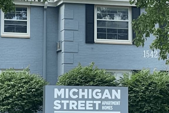 A blue house with a sign in front that says Michigan Street Apartment Homes. at Michigan Street Apartment Homes, Apartments, Grand Rapids  , MI