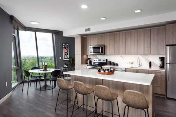 A modern kitchen with a bar stool and a dining table.