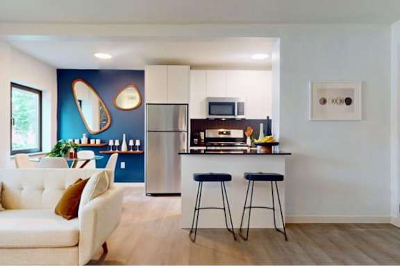 A modern kitchen with a white couch and a blue accent wall.