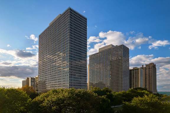A large glass building stands in front of a skyline.