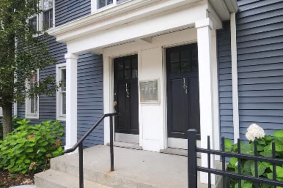A blue house with a white door and a black gate.