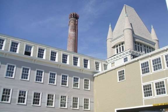 A building with a tall chimney and a tower with a pointed roof.