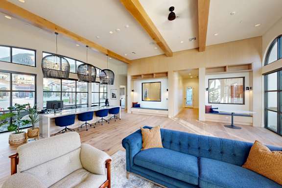 a living room with blue couches and chairs and large windows