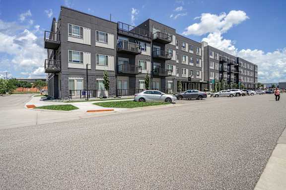 Apartment building with cars parked in front.