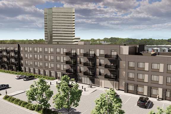 A modern building complex with a parking lot in front.