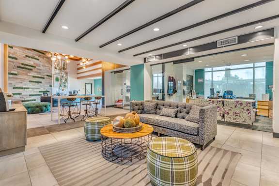 a living room with couches and tables and a kitchen in the background