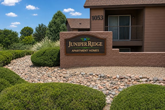 A brown building with a sign that says Juniper Ridge Apartment Homes.