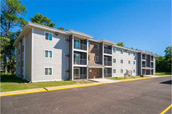 an exterior view of an apartment building with a parking lot