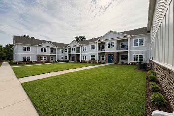 A white building with a grey roof and a green lawn in front.