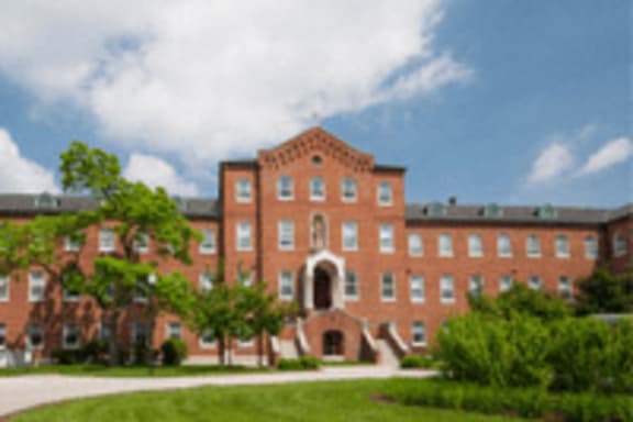 A large red brick building with a green lawn in front.