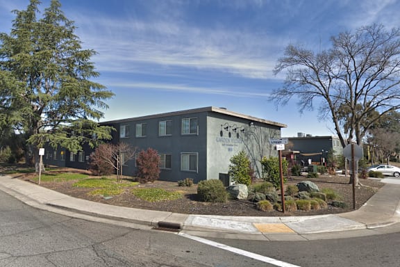 A street view of a building with a grey facade and a white car parked in front.