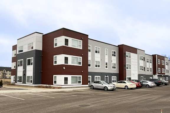 A parking lot in front of a multi-story apartment building.