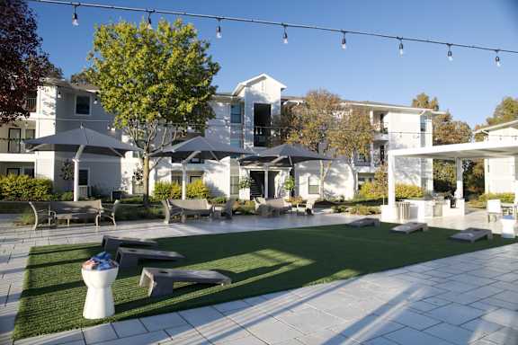 A white and black building with a tree in front of it.