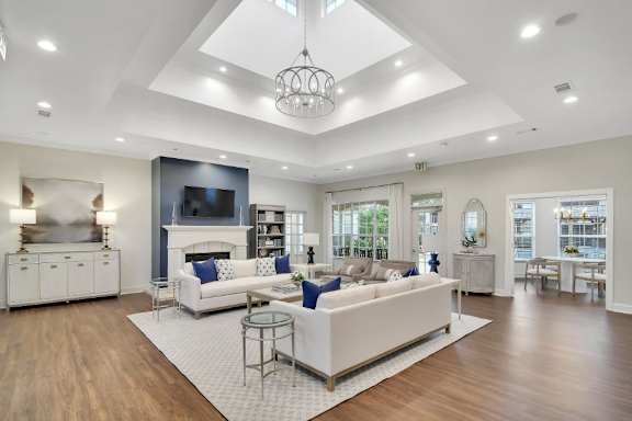 a living room with white couches and a tv on the wall at Ashford Place Apartment Homes, Mississippi