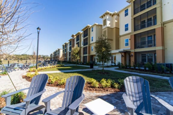 a patio with two chairs and a table in front of an apartment building