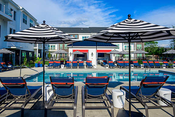 A pool area with chairs and umbrellas.