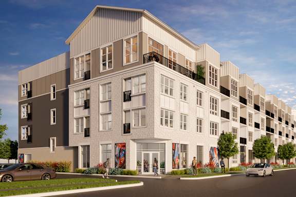 A modern apartment building with a parking lot in front.