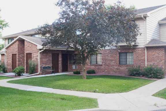 A brick house with a tree in front.