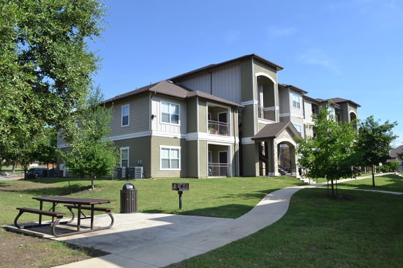 an apartment building with a sidewalk and picnic table in front of it