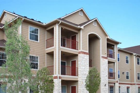 a large apartment building with a balcony and trees